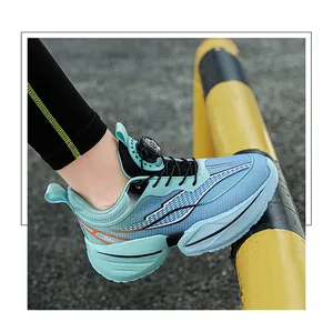 Detail of light blue boys' running shoe with rotary dial buckle on yellow barrier.