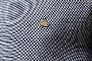 Macro detail of the knit texture and metal triangle badge on a men's winter sweater