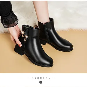 Detailansicht von schwarzen Damen-Stiefeletten mit Herz- und Sonnenanhängern und Blockabsatz