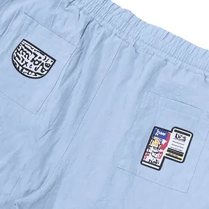 Zoom sur les écussons graphiques des poches arrière du pantalon en lin bleu clair