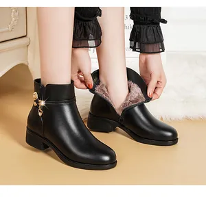 Detailansicht schwarzer Stiefeletten mit Plüschfutter und goldenem Herzanhänger.