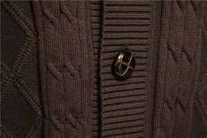 Close-up detail of dark brown cable knit fabric and decorative button on men's sweater
