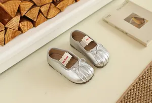 Gros plan de ballerines argentées pour bébé avec nœud et fini métallique élégant.