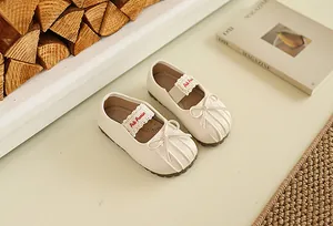 Gros plan de douces chaussures Mary Jane crème pour bébé avec nœuds et dentelle