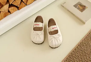 Gros plan de chaussures Mary Jane crème avec nœud et détails plissés pour les bébés
