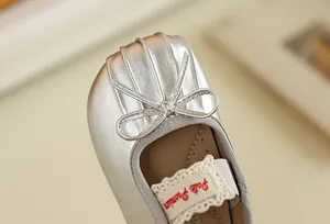 Détail de ballerines argentées pour bébé avec un nœud délicat et une finition métal