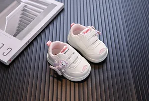Close-up of white baby sneakers with a cute cartoon dinosaur and pink accents.