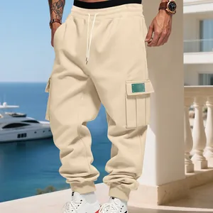 Close-up of beige men's cargo sweatpants with multi-pockets on a sunny terrace