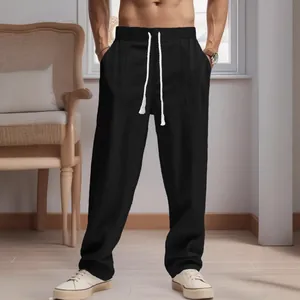 Close-up view of men's loose black linen trousers featuring a white drawstring waist