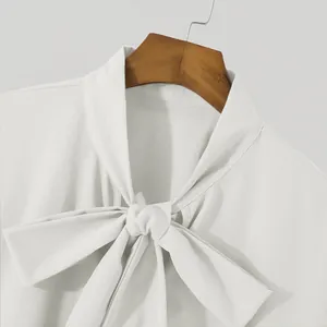 Macro view of elegant white shirt featuring a sophisticated tie-neck bow design