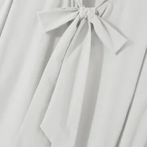 Close-up of mens loose fit long sleeve shirt with elegant bow tie neckline detail.