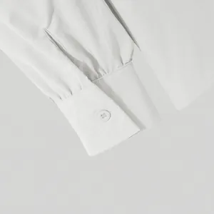 Close-up of a white men's shirt cuff with button detail and pleated sleeve texture