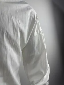 Close-up of white long sleeve shirt with textured fabric and dropped shoulder design detail