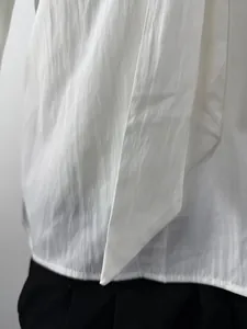 Macro view of white long-sleeved shirt with unique tie-style decorative fabric and texture