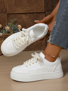 Dettaglio ravvicinato di sneaker bianche platform con spessi lacci intrecciati