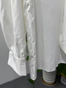 Detailed macro view of white men's shirt sleeve cuff showing fine stitching and fabric texture.