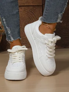 Dettaglio ravvicinato di eleganti sneaker bianche con plateau e lacci intrecciati