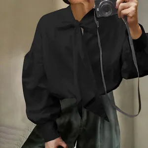 Detail view of a black tie-neck long sleeve shirt with dropped shoulders and lantern sleeves