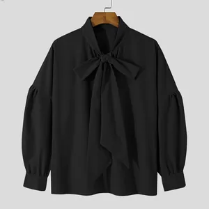 Close-up detail of black loose men's shirt with unique bow-tie collar and lantern sleeves