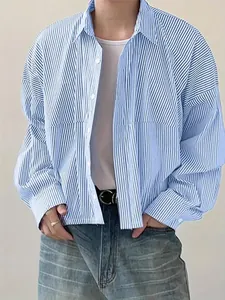 Close-up detail of a men's blue and white striped loose casual long-sleeve shirt worn open