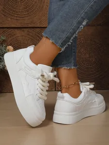 Primo piano di sneaker bianche chunky da donna con suola spessa e lacci intrecciati
