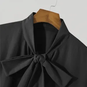 Macro view of the elegant bow-tie neckline detail on a black men's loose fit shirt