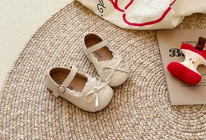 Dettaglio scarpe Mary Jane panna per bambina con bordo in pizzo e decorazione a fiocco
