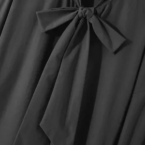 Detailed close-up of a black long-sleeved shirt featuring a stylish front bow-tie design.