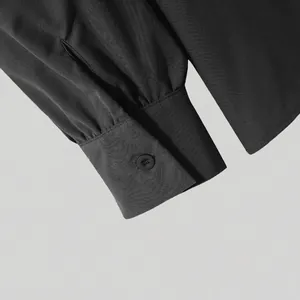 Macro detail of black men's long sleeve shirt cuff with button and pleated texture