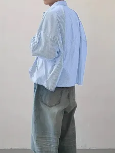 Side-back view of a men's loose blue and white vertical striped long-sleeved shirt.