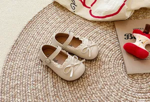 Dettaglio scarpe Mary Jane beige per bambini con pizzo e fiocco su un tappeto intrecciato