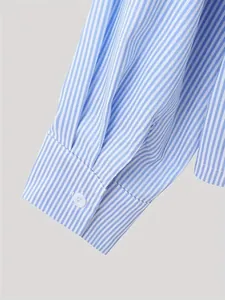 Close-up detail of a light blue and white vertical striped shirt sleeve cuff with button