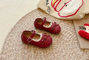 Vista dettagliata di scarpe Mary Jane rosse per bambina con pizzo e fiocco decorativo