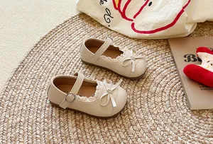 Dettaglio di scarpe Mary Jane beige per bambine con pizzo e un grazioso fiocco