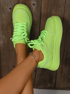 Sneaker platform verde neon con lacci spessi su sfondo di pavimento in legno