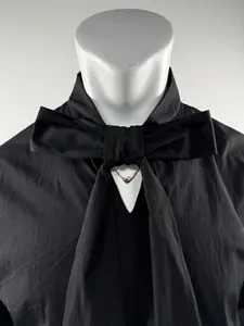 Detail of black long-sleeved shirt featuring a unique oversized bow necktie design.