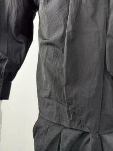 Close-up of black men's shirt featuring a unique tie-like collar design and textured fabric.