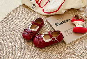 Dettaglio di scarpe Mary Jane rosse per bambine con bordi in pizzo e fiocchi eleganti