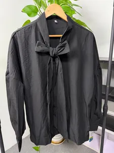 Detail of black loose-fit shirt featuring a stylish drop shoulder and bow tie collar