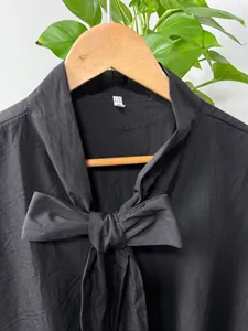 Close-up of black drop-shoulder shirt with unique bow-tie neckline detail