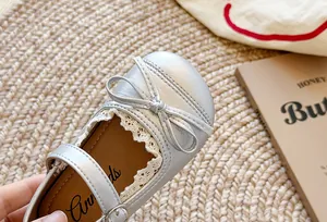Primo piano di eleganti scarpe Mary Jane in pelle argento con fiocco per bambine