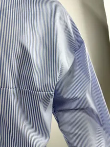 Detail shot of blue vertical stripes on a men's loose long-sleeved cotton shirt.