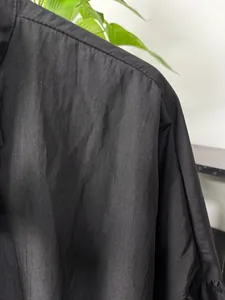 Detailed macro shot showing the black fabric texture and shoulder seams of a men's shirt