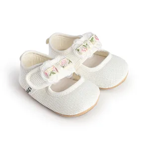 Close-up detail of breathable white mesh infant Mary Jane shoes with floral bow accents