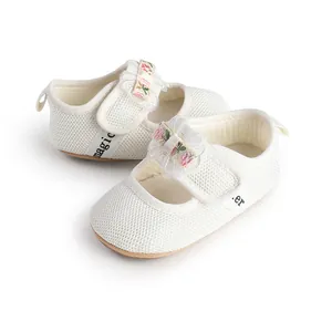 Close-up of white mesh baby princess shoes with floral bow straps and soft soles.