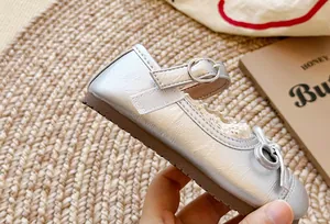 Primo piano di scarpa Mary Jane argento per bambina con bordo in pizzo e fiocco
