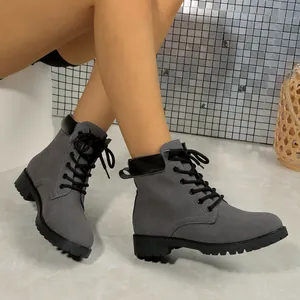 Side view detail of grey suede-style lace-up Martin boots shown on model legs.