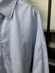Close-up detail of blue and white vertical striped shirt showing shoulder stitching