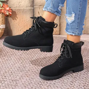 Close-up of black lace-up Martin boots with textured rug and brick wall background