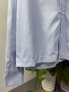 Close-up detail of the hem and sleeve on a blue and white vertical striped shirt.